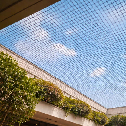 Bird netting tensioned across roof opening in shopping mall, preventing bird mess and damage to the property.