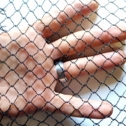 Close up of 5m bird proof netting with hand showing the 1cm square hole size.